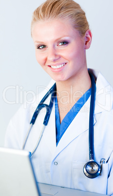 Doctor working on a laptop looking at camera
