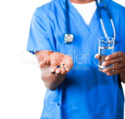 Close-up of an friendly doctor in scrubs with pills and glass of water