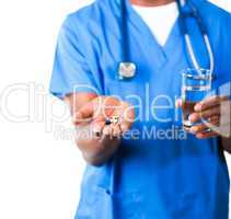 Close-up of an friendly doctor in scrubs with pills and glass of water