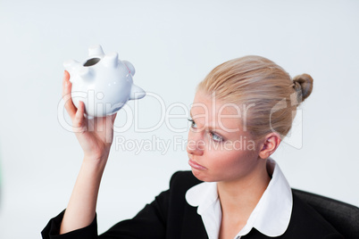 Sad Business woman looking into Piggy Bank