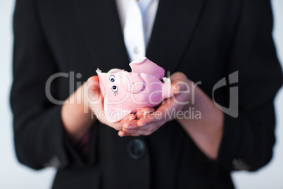 Business woman holding a broken piggy bank