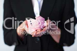 Business woman holding a broken piggy bank