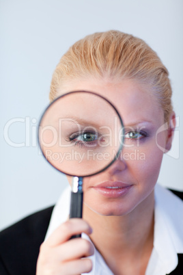 Serious Business woman looking through a magnifying Glass