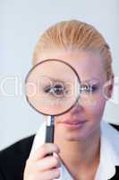 Serious Business woman looking through a magnifying Glass