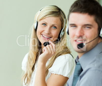 Two business people smiling at the camera with headsets