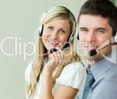 Two business people smiling at the camera with headsets