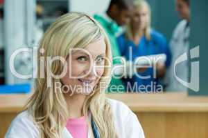 Blonde Ärztin - im Hintergrund Klinikpersonal
