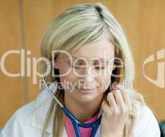 Blonde Ärztin hat Stethoskop im Ohr