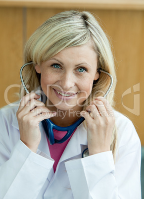 Lächelnde blonde Ärztin hat Stethoskop im Ohr