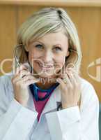 Lächelnde blonde Ärztin hat Stethoskop im Ohr