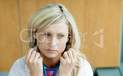 Blonde Ärztin hat Stethoskop im Ohr