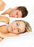 Couple lying in bed and woman looking at the camera