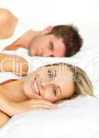 Couple resting in bed and woman smiling at the camera