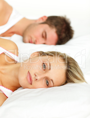 Couple lying in bed and woman looking at the camera