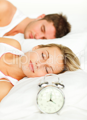 Couple in bed with alarm clock going off