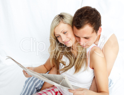 Couple reading a newspaper in bed