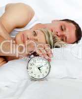 Couple in bed with alarm clock going off