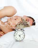 Couple in bed with focus in alarm clock