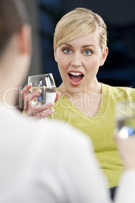 A Surprised Young Blond Woman Drinking With A Friend