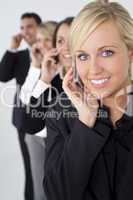 Beautiful Blond Woman On Cell Phone With Team Behind Her