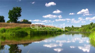 Rural landscape with  river,lone tree and flying clouds