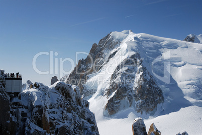 Steep snow peak of Mont Blanc and view ground with persons