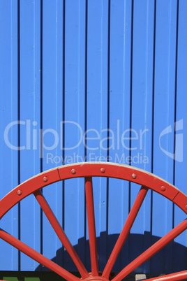 Blaue Bretterwand und rotes Wagenrad