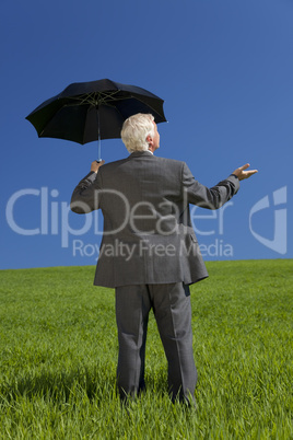 Businessman In A Green Field With Umbrella