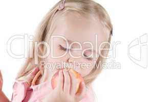 Little girl eating peach in studio