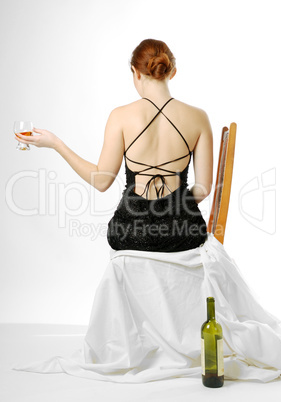 Young woman sitting with wineglass, rear view