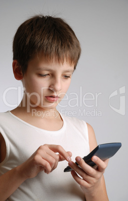 Pre-teen boy with mobile phone on light background