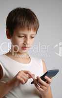 Pre-teen boy with mobile phone on light background