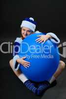 Female Santa embracing large blue sphere
