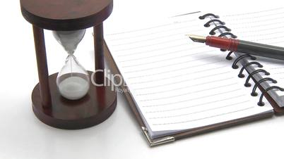 Hourglass, pen and lined notebook