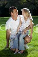 Father With Daughter On Knee Smiling In A Park