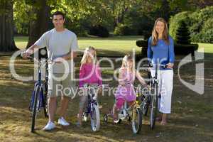 Happy Family Riding Bikes In A Park