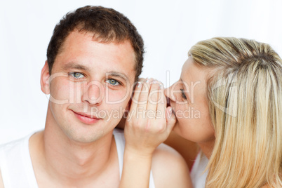 Junge Frau flüstert einem Mann etwas ins Ohr