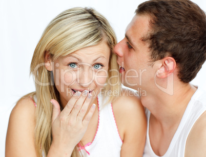 Junger Mann raunt einer Frau etwas ins Ohr