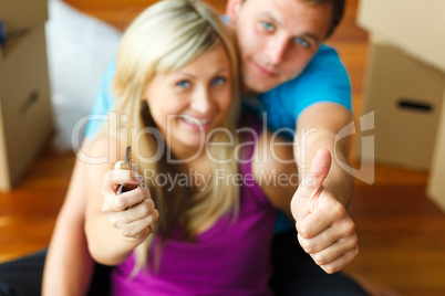 Woman and man holding a key with thumbs up. Buying new house