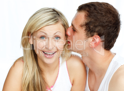 Junger Mann raunt einer Frau etwas ins Ohr