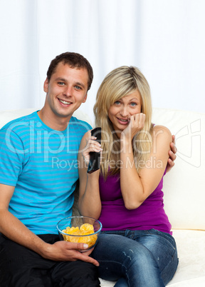 Couple watching a film on television and eating crisps