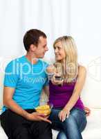 Lovers watching television and eating crisps