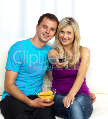 Happy couple watching television and eating crisps