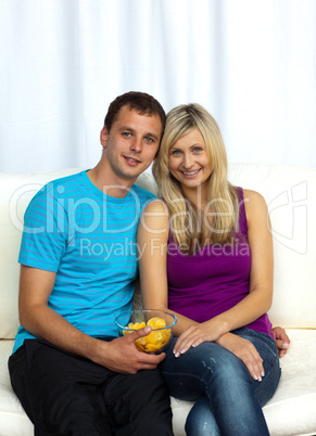 Couple watching television and eating crisps