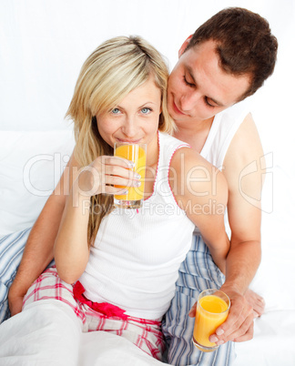 Junges Paar trinkt Orangensaft im Bett
