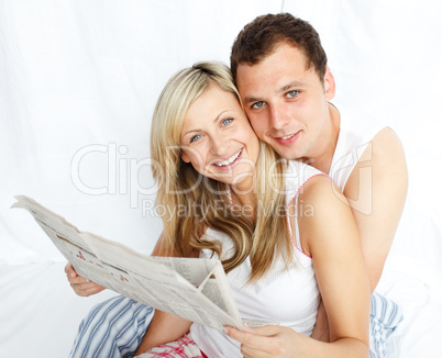 Junges Paar liest Zeitung im Bett