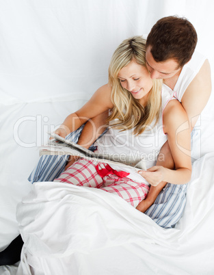Junges Paar liest Zeitung im Bett