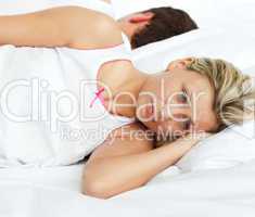 Junges Paar liegt Rücken an Rücken im Bett