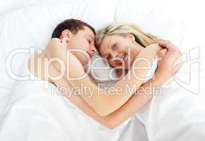 Junges Paar liegt Arm in Arm im Bett