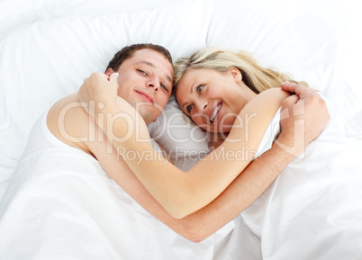 Junges Paar liegt Arm in Arm im Bett